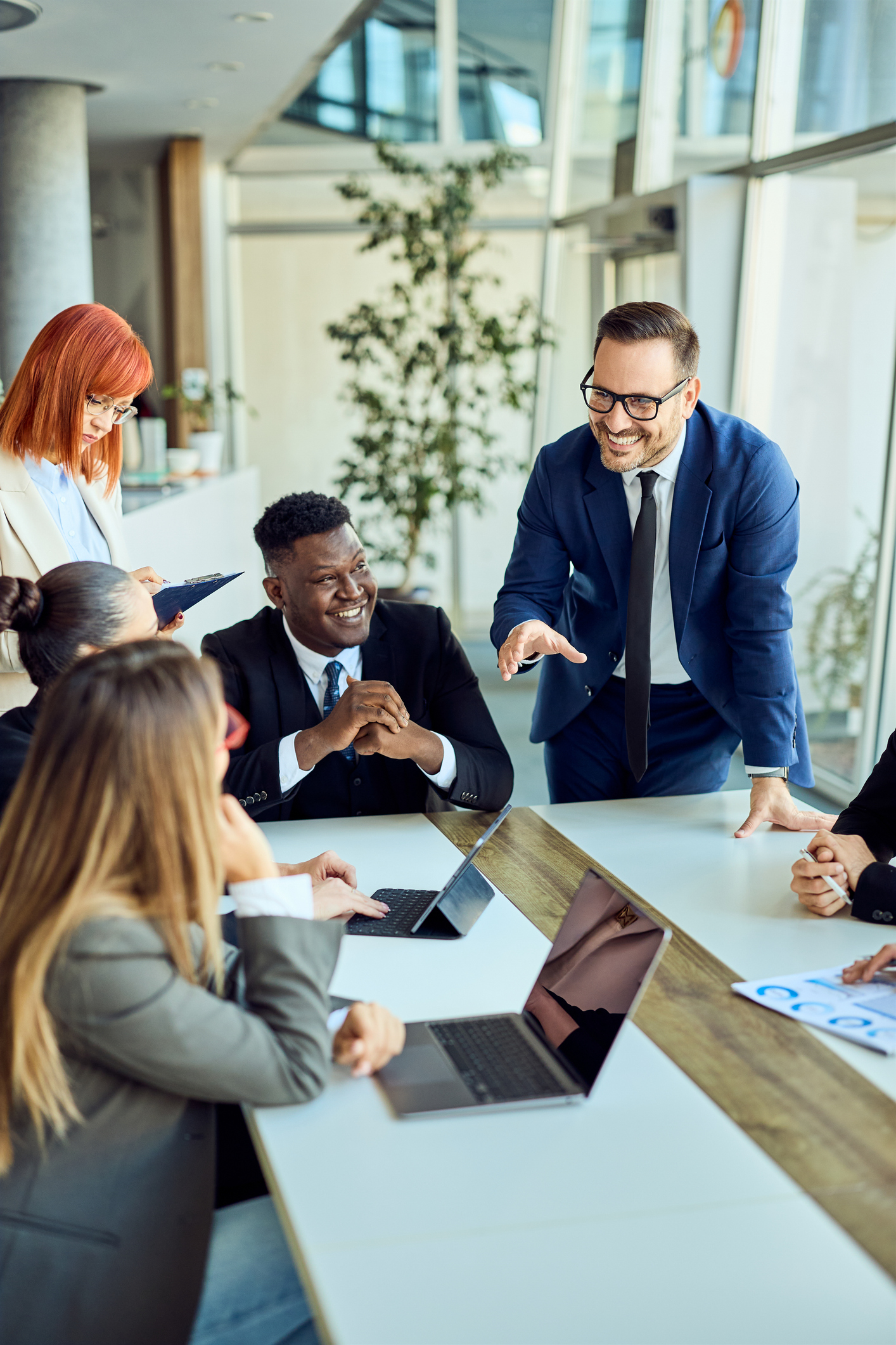 Business professionals collaborating in a meeting with laptops in a modern office.